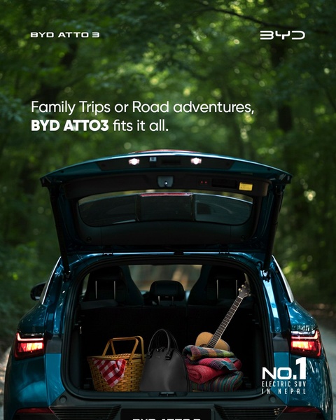 The creative displays an open SUV trunk packed with travel essentials like a picnic basket, handbag, and guitar against a lush forest backdrop.
