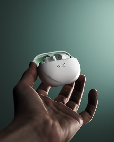 A close-up, high-contrast shot of white wireless earbuds held in a hand against a muted teal background.