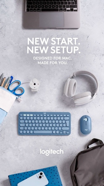A high-angle, top-down product photography shot showcasing a laptop, blue wireless keyboard, mouse, headphones, and office accessories on a light gray surface.