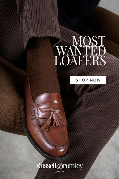 A close-up, high-fashion shot of a brown leather tassel loafer worn with matching socks and corduroy trousers, conveying a sense of premium quality and seasonal comfort.