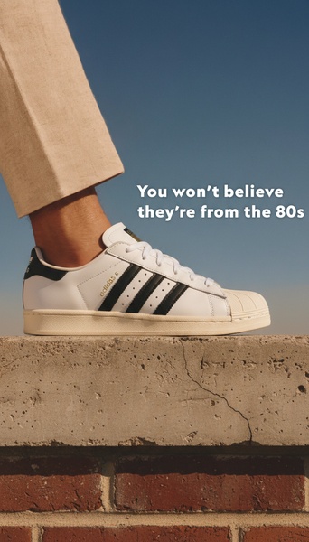 A high-contrast, vertical shot of a classic white running shoe resting on a brick wall against a deep blue sky, featuring a provocative text-based hook.