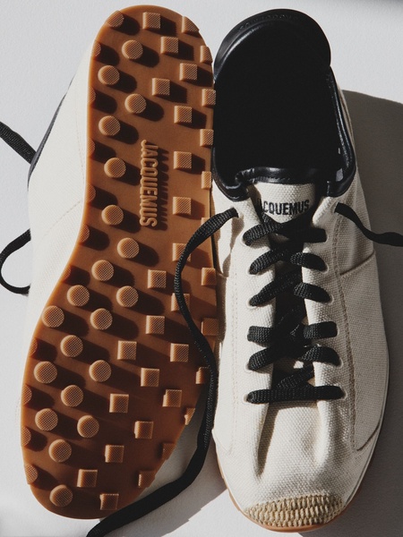 A high-end, top-down product shot of a canvas sneaker, highlighting the texture of the sole and the branding through natural, high-contrast lighting.