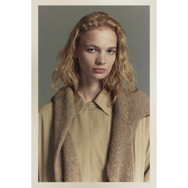 A high-quality, close-up portrait of a model wearing a soft knit cardigan, utilizing a neutral color palette and a clean, editorial aesthetic.