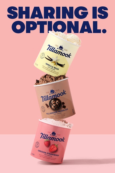 A vertical image showing a tall, impossible stack of three Tillamook ice cream containers against a solid, soft-toned pink background.