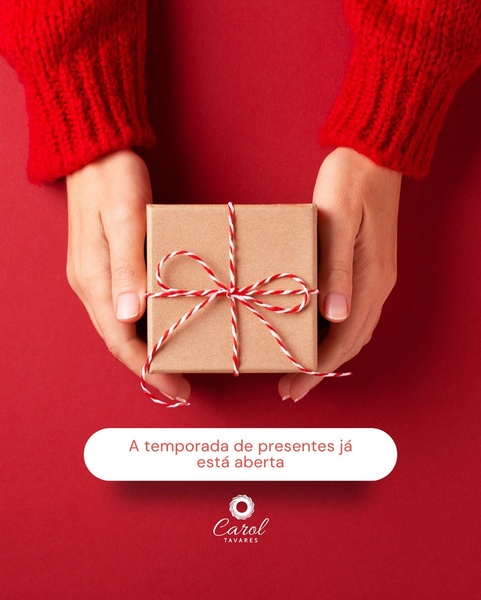 A clean, high-impact shot showing a person holding a small, elegantly wrapped gift box against a bold red background.