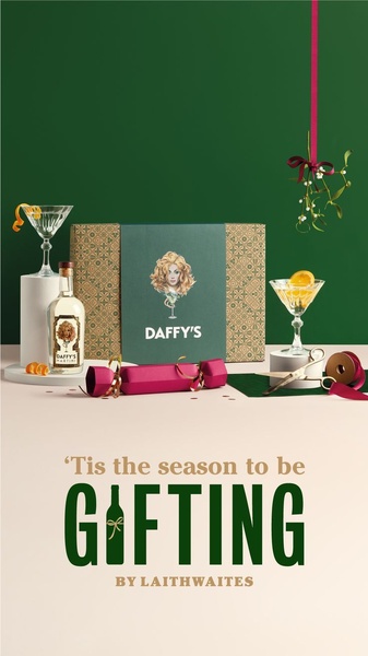 A festive product shot featuring a martini cocktail, gin bottle, and gift box styled for the holiday season with mistletoe and a cracker.