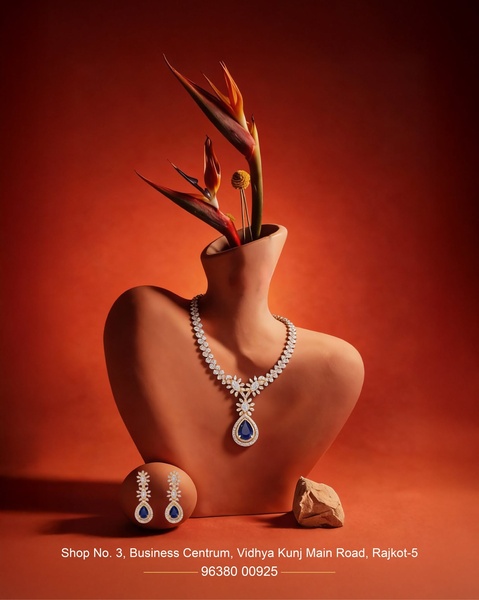 A high-end jewelry set featuring a pendant necklace and earrings displayed on a clay-tone bust with botanical elements.
