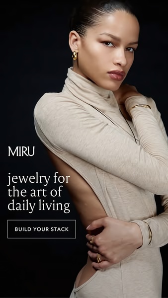 A high-fashion, minimalist editorial shot featuring a model wearing gold jewelry against a dark background, emphasizing lifestyle luxury.