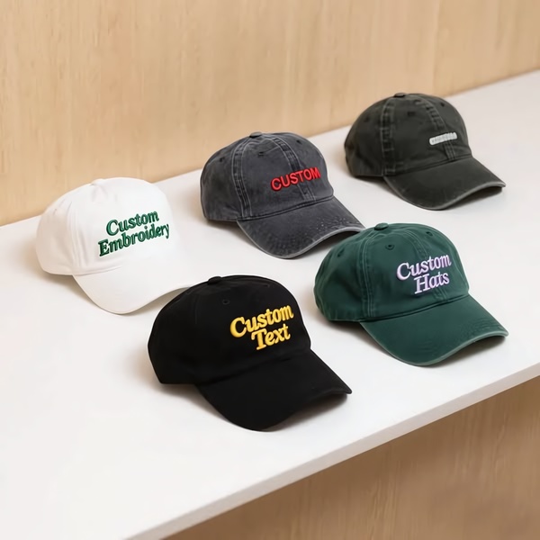 A high-quality, studio-lit photograph displaying five custom-embroidered caps in different colors arranged neatly on a clean white surface.
