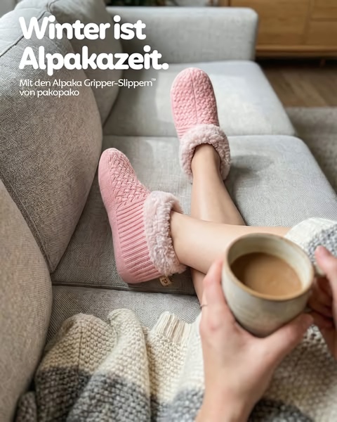 A high-angle shot of a person wearing soft pink slippers on a couch with a coffee, emphasizing comfort.