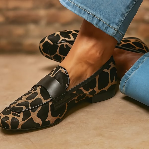A high-fidelity close-up shot of an animal print loafer on a foot, emphasizing texture, pattern detail, and the silhouette of the shoe.