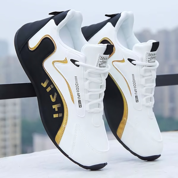 A clean, studio-lit display of a white and black running shoe with gold accents, positioned against a neutral, blurred architectural background.