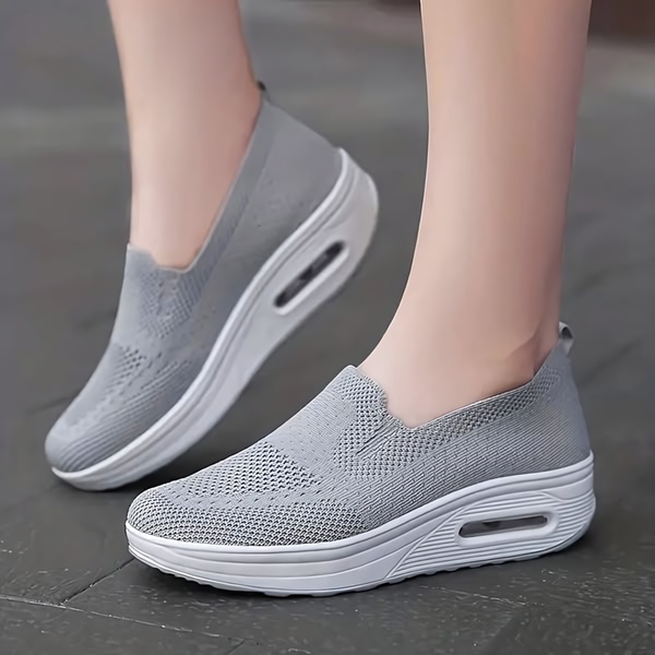 A clean, studio-lit image focusing on the ergonomic design and cushioning features of a modern slip-on walking shoe.