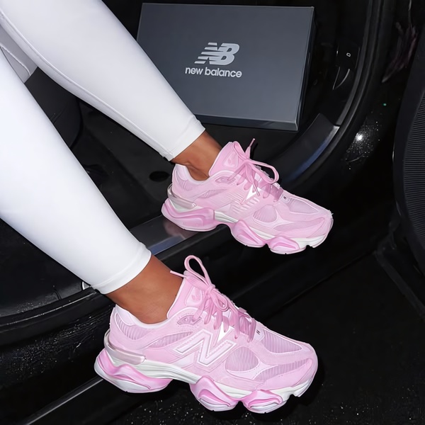 A high-contrast, lifestyle-focused product shot showcasing pink running shoes worn in a car setting, emphasizing color and brand visibility.