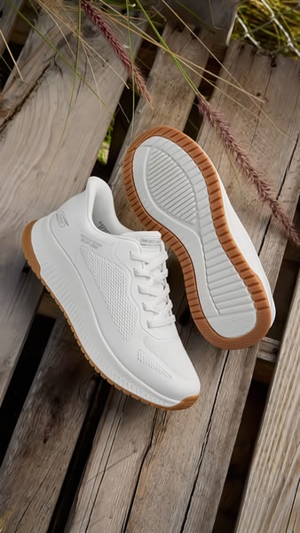 A clean, high-angle lifestyle shot featuring a pair of white sneakers placed on rustic wooden slats, emphasizing texture and product detail.