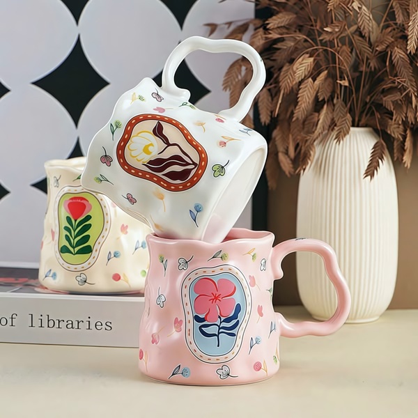 A high-quality, balanced 1:1 image featuring two uniquely designed ceramic flower mugs in a warm, artistic lifestyle setting.