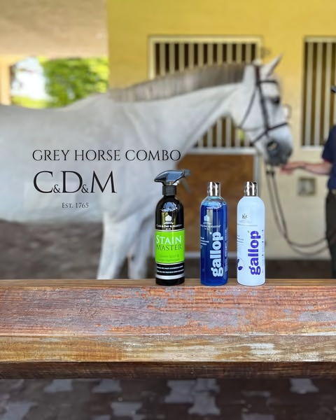 A clean, eye-level product hero shot featuring three grooming bottles placed on a wooden surface with a horse in the blurred background.