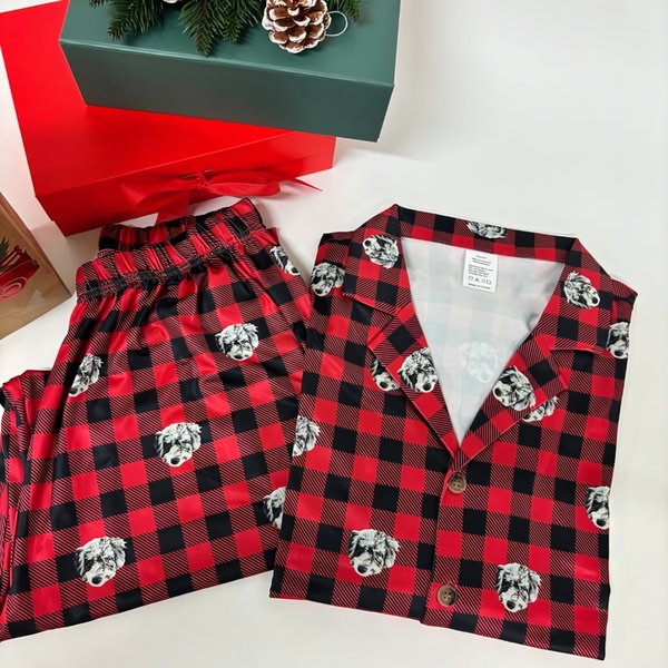A high-quality flat-lay shot of holiday-themed red and black buffalo plaid pajamas featuring custom dog photos.