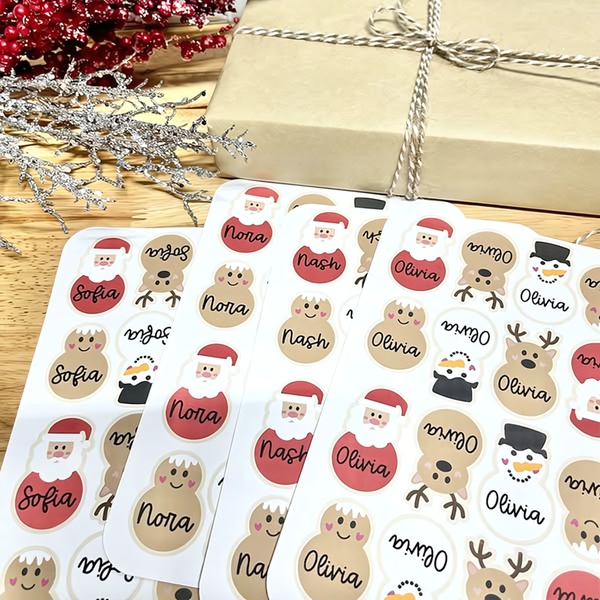 A top-down, clean product shot of custom-printed holiday stickers featuring Santa, reindeer, and snowman designs with individual names.