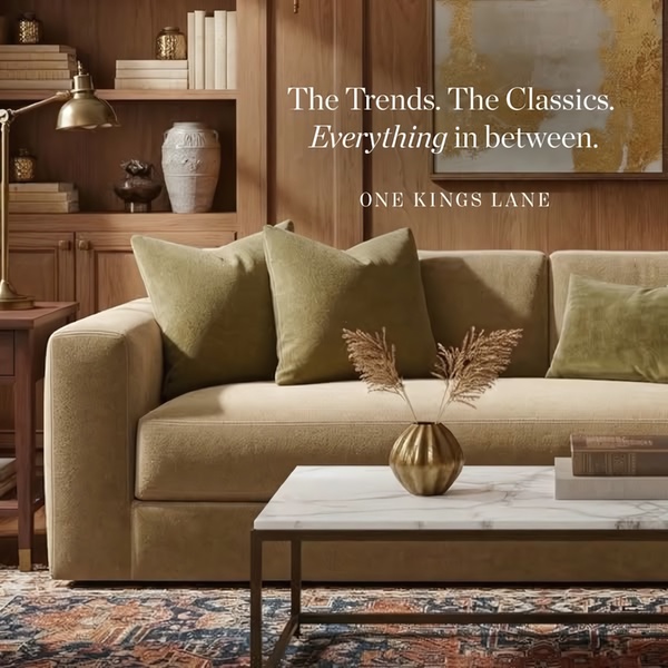 A sophisticated lifestyle photograph of a velvet sofa in a warm, wood-paneled room with minimalist decor and soft, natural lighting.