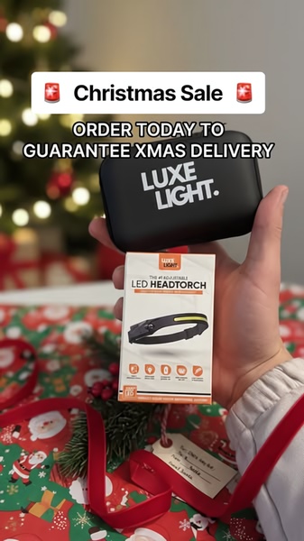 A close-up, hand-held shot of an adjustable LED headtorch in its packaging, positioned against a blurred, festive Christmas tree backdrop with a clear, urgent sale headline.