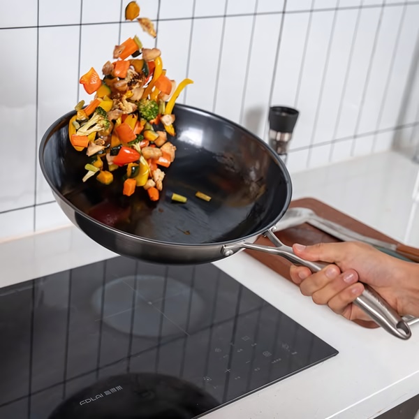 This ad creative uses a high-speed motion shot of vegetables mid-air above a sleek black wok to emphasize the product's professional kitchen capability.