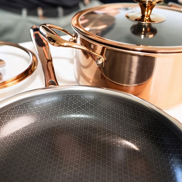 A close-up, high-quality product hero shot of copper cookware sets on a clean white background, focusing on material texture and finish.