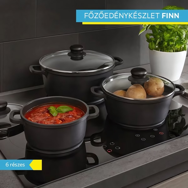 A clean, high-contrast studio shot of a 6-piece black cookware set on a modern induction stovetop with a green garnish for visual interest.