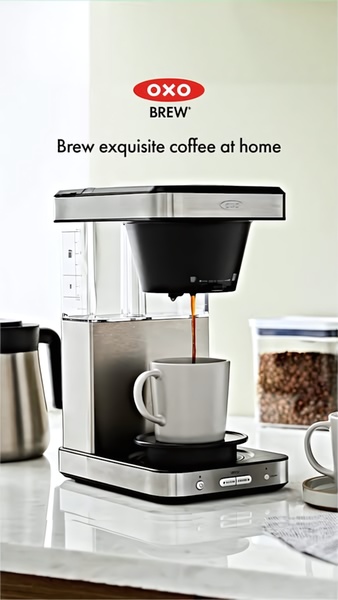 A high-quality, close-up shot of a modern stainless steel coffee maker in a bright kitchen, emphasizing the brewing process and premium aesthetic.