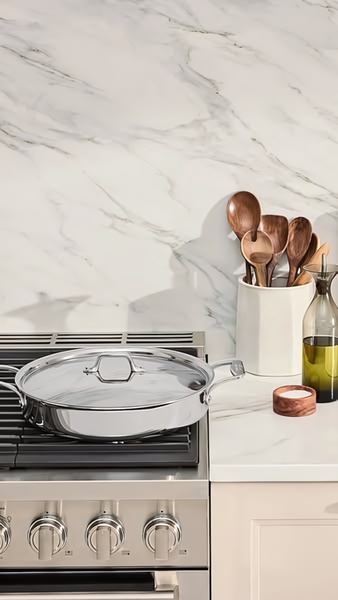 A high-end, clean-focused product shot of a stainless steel skillet on a range, emphasizing kitchen utility and aesthetic appeal.