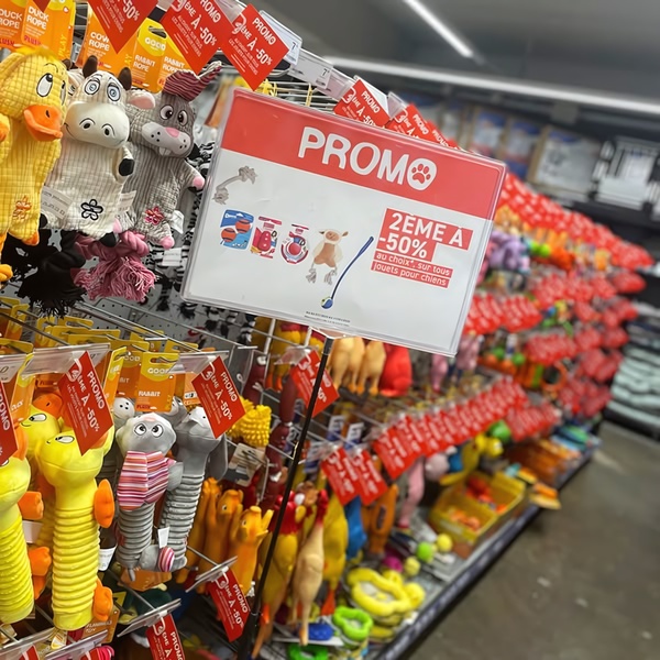A high-visibility, in-store promotional sign advertising a 50% discount on the second dog toy purchased.