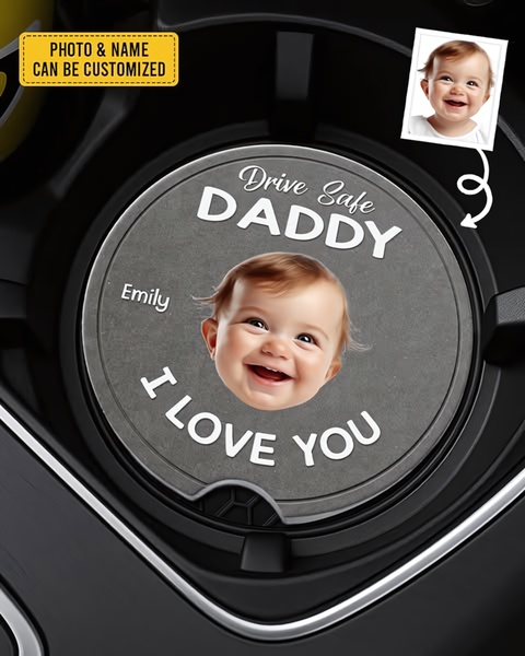A close-up shot of a car cup holder featuring a custom-printed stone coaster with a baby's photo and a heartfelt message to a parent.