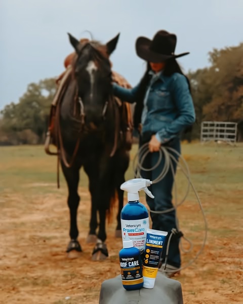A high-quality lifestyle image featuring Vetericyn animal care products placed in the foreground with a horse and handler in a soft-focus ranch background.