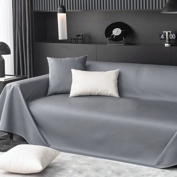 A high-end, minimalist presentation of a sofa cover in a dark, modern living room setting, emphasizing product texture and color.