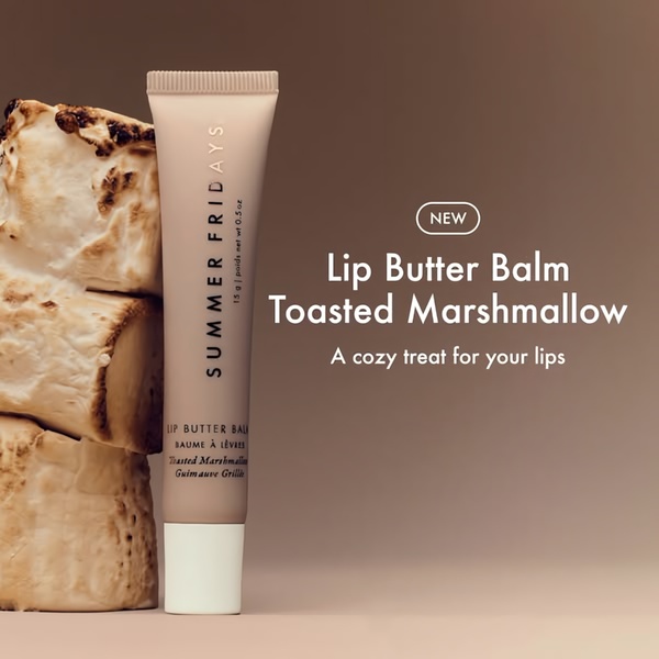 A high-contrast product-centric image featuring a lip balm tube beside toasted marshmallows against a warm, neutral background.