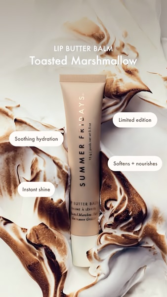 A close-up vertical image of a branded lip balm tube surrounded by a creamy, toasted marshmallow visual to emphasize scent and texture.