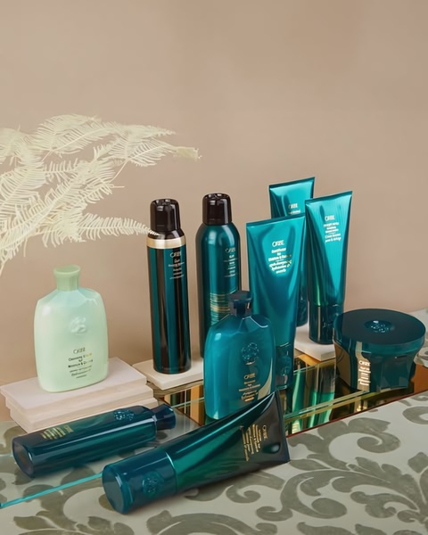 A sophisticated, high-end product display showcasing a collection of professional hair care bottles and containers on a mirrored surface.