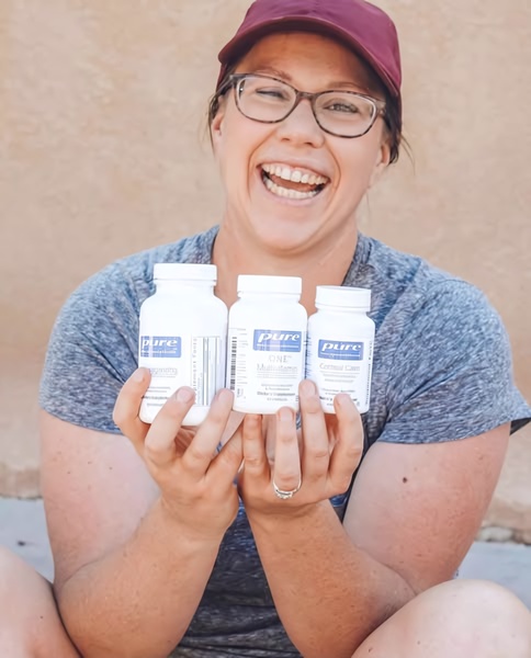 A smiling user holds up three different supplement bottles in a casual, relatable setting to build social proof and authenticity.