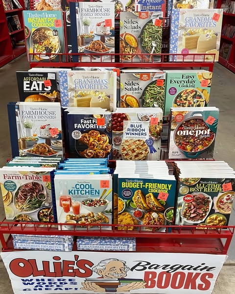 A high-density, eye-level photograph of a bookstore rack filled with various cooking and recipe books, centered around a 'Bargain Books' promotional sign.