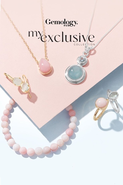 A clean, high-key studio shot featuring a variety of gemstone necklaces, earrings, and rings arranged on a soft pink and light blue background.