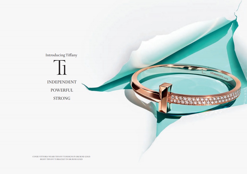 A high-end product hero shot featuring an 18k rose gold bracelet emerging from a signature blue surface behind a white paper tear.