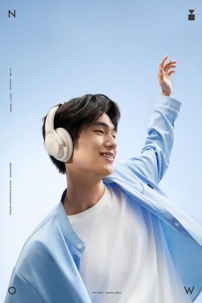 A portrait-oriented, bright lifestyle shot featuring a model wearing headphones, focusing on a sense of freedom and clear audio.