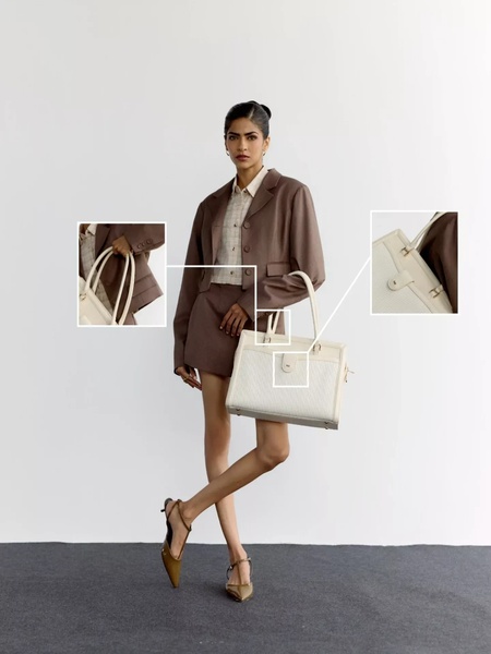 A high-fashion, minimalist style ad that uses visual callouts to highlight the specific hardware and texture of a premium handbag.
