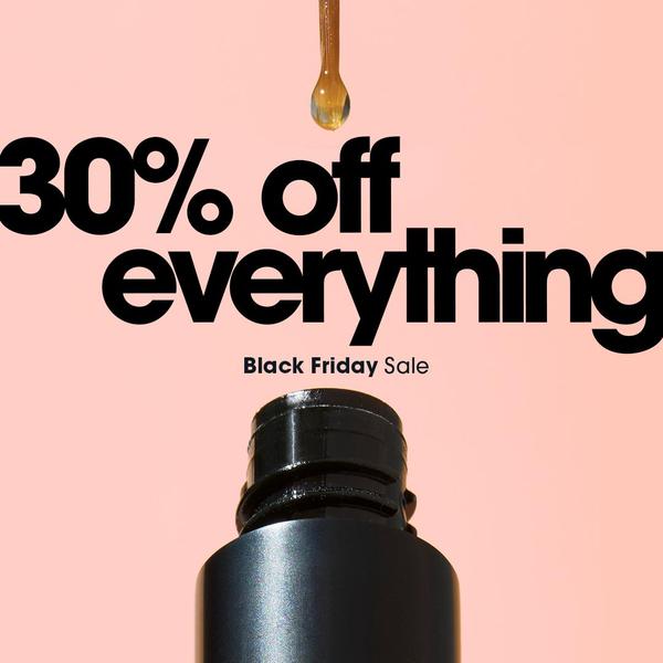 A minimalist product shot featuring a single drop of serum above an open bottle against a soft pink background to highlight a site-wide discount.