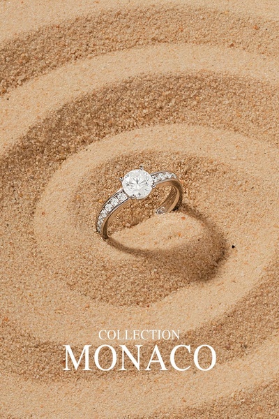 A high-end, minimalist presentation of a diamond engagement ring resting in spiral-patterned desert sand.
