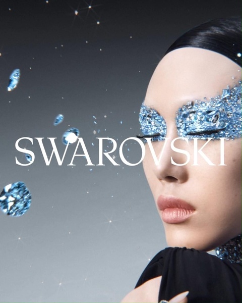 A close-up fashion portrait featuring elaborate blue crystal eye makeup, highlighting the sparkle and premium nature of the jewelry brand.