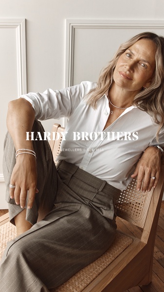 A high-end portrait featuring a model in business casual attire highlighting a silver bracelet, shot in a bright, clean, and professional studio aesthetic.