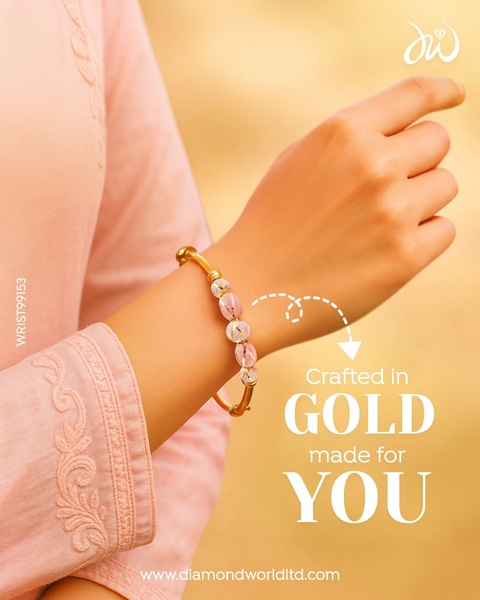 A close-up lifestyle image featuring a model wearing a gold bracelet with unique textured beads, set against a warm, soft-focus background.