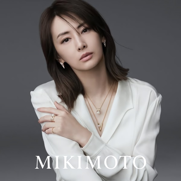 A refined, high-end portrait of a model wearing a layered pearl necklace, focusing on product elegance and brand identity.