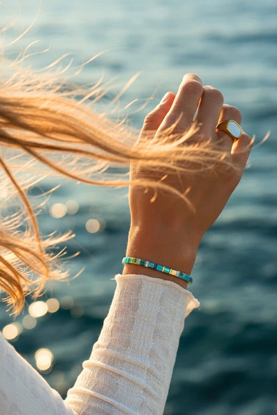 A high-quality lifestyle shot of a beaded bracelet on a woman's wrist at sunset, emphasizing a premium and aspirational vibe.